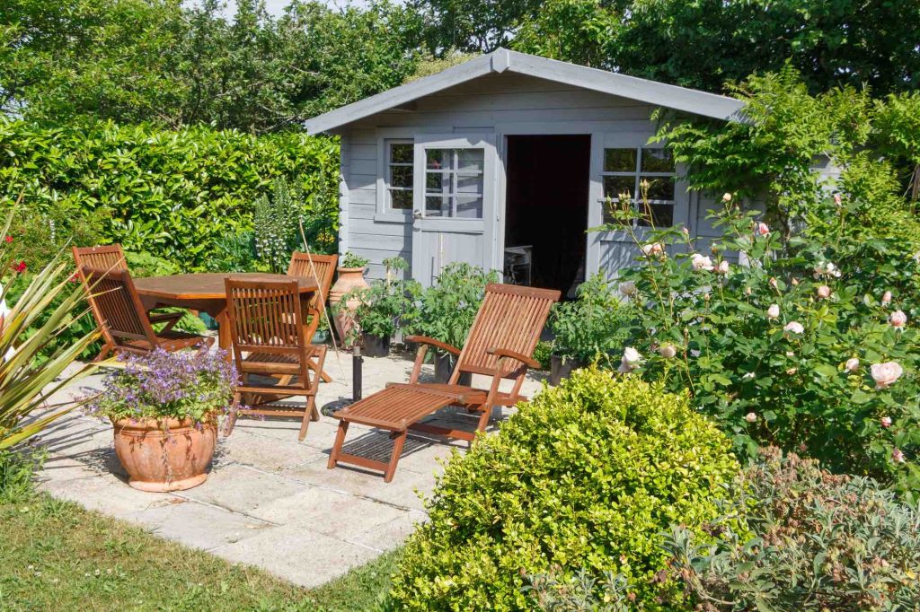 Grey shed with terrace and wooden garden furniture